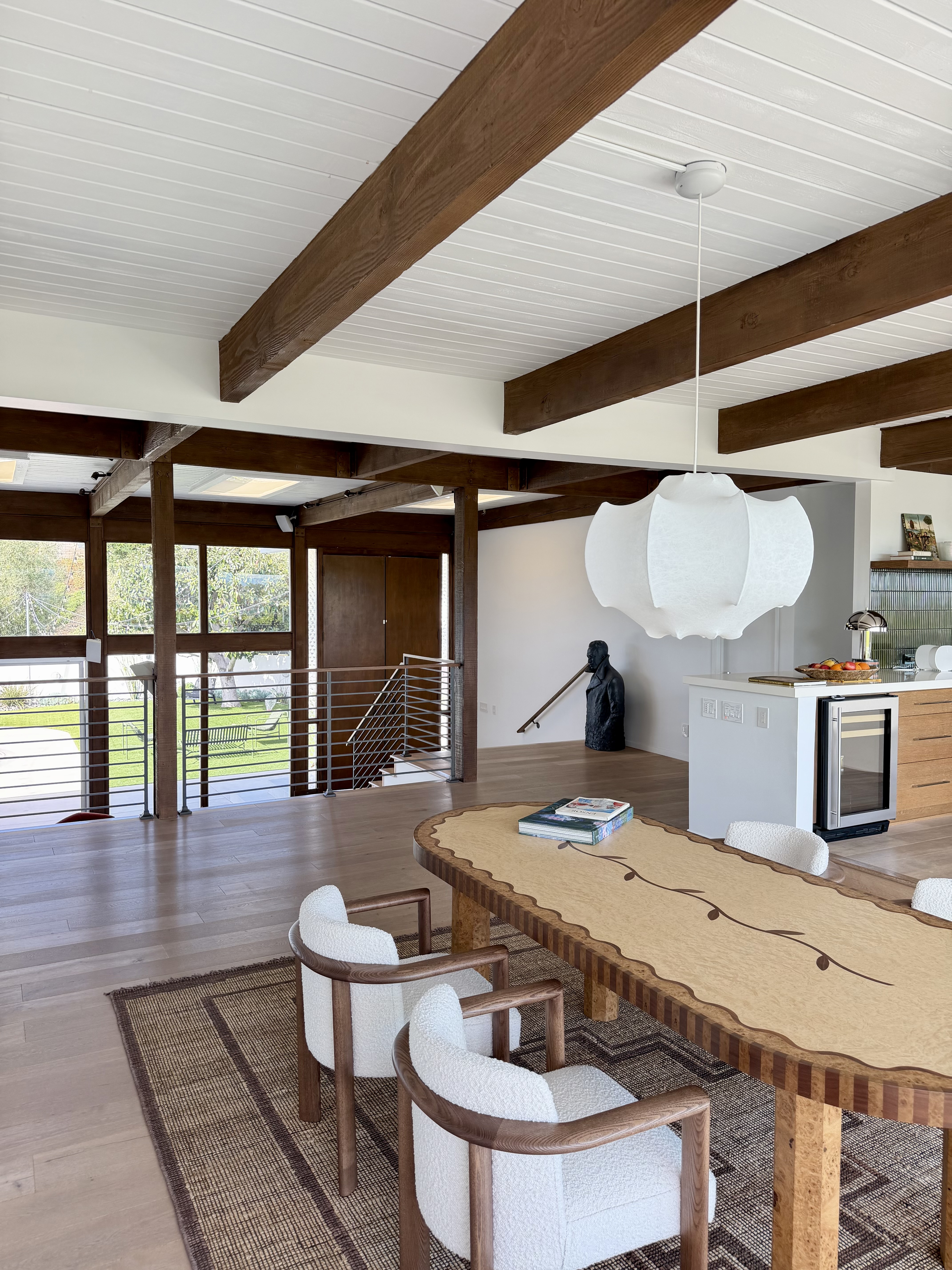 Mid-century modern dining room with wood beam ceiling and pendant light over a wood dining table